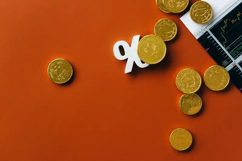 Gold coins with percentage symbol and financial charts